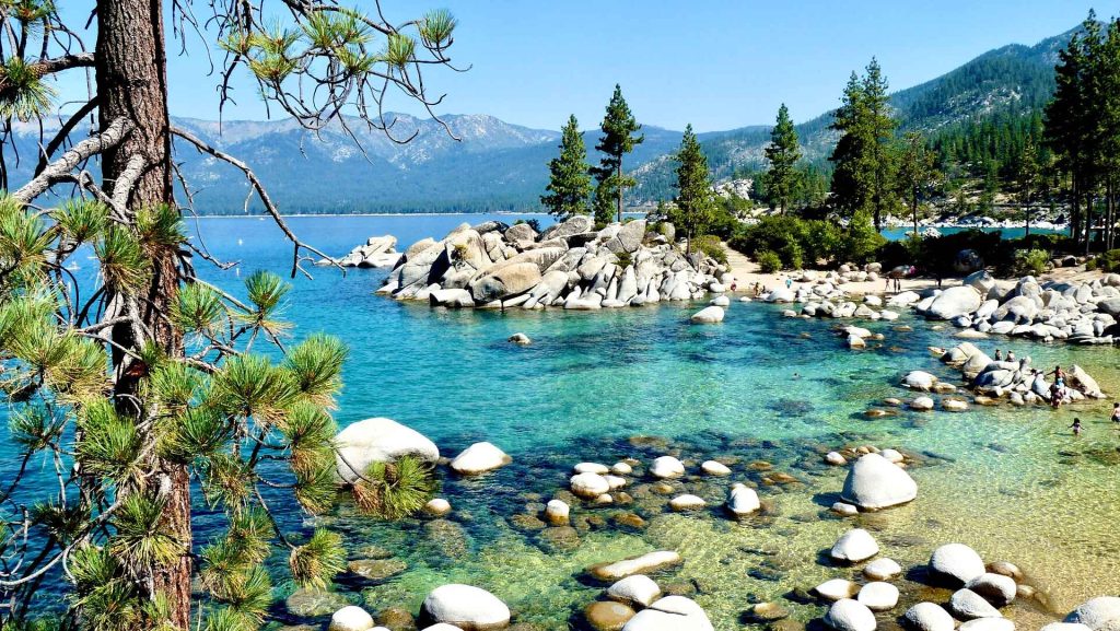 Tranquil scene at Lake Tahoe, straddling California and Nevada, offering a serene getaway for couples. The picturesque lake is framed by towering pine trees and distant snow-capped peaks. Secluded beaches provide intimate settings for picnics or sunset views, while nearby hiking trails offer opportunities for romantic walks amidst stunning natural scenery.