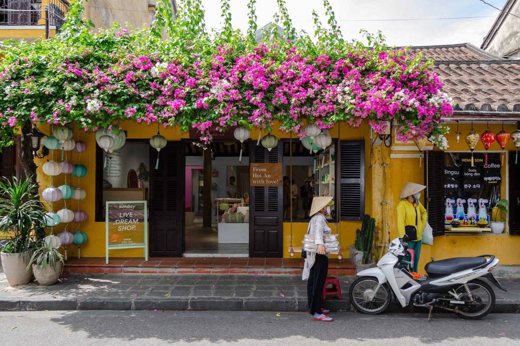 Rich display of Vietnamese culture, featuring traditional ao dai dresses, bustling street markets, and vibrant lanterns hanging in ancient towns. The scene includes people practicing traditional crafts, such as pottery and weaving, alongside performances of folk music and dance, all set against the backdrop of historical temples and pagodas.