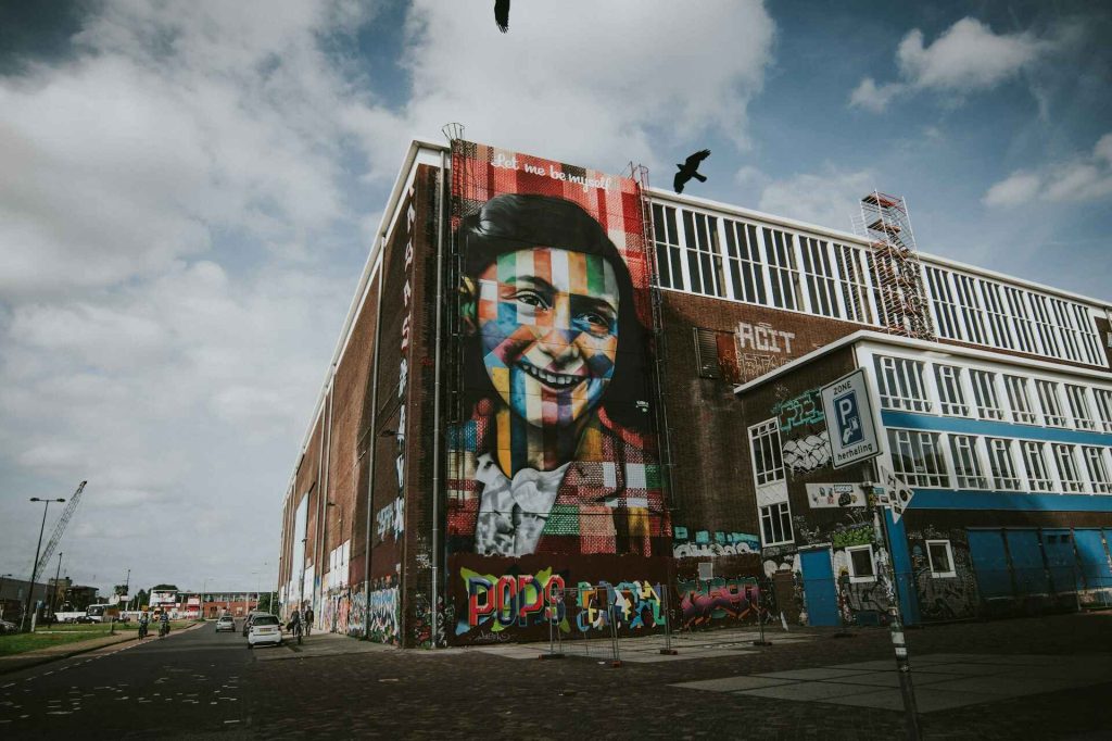 Portrait of Anne Frank painted on a large wall, symbolizing her enduring legacy.